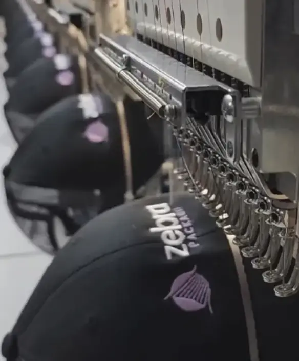Embroidery machine working on a black cap
