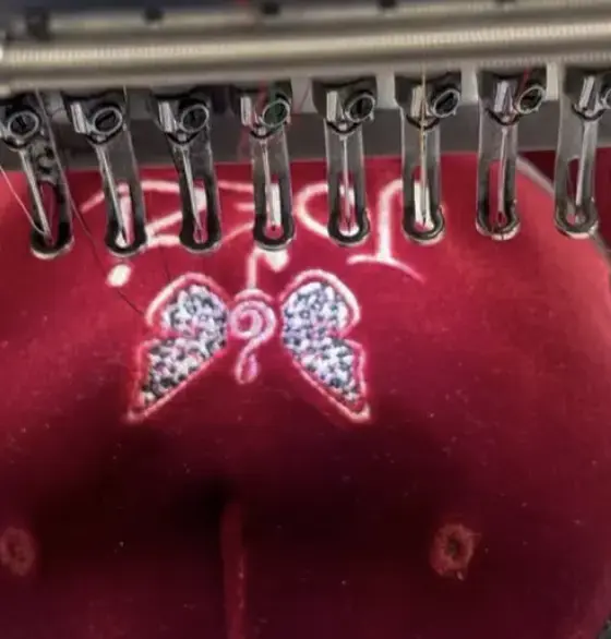Butterfly motif being embroidered onto a red cap