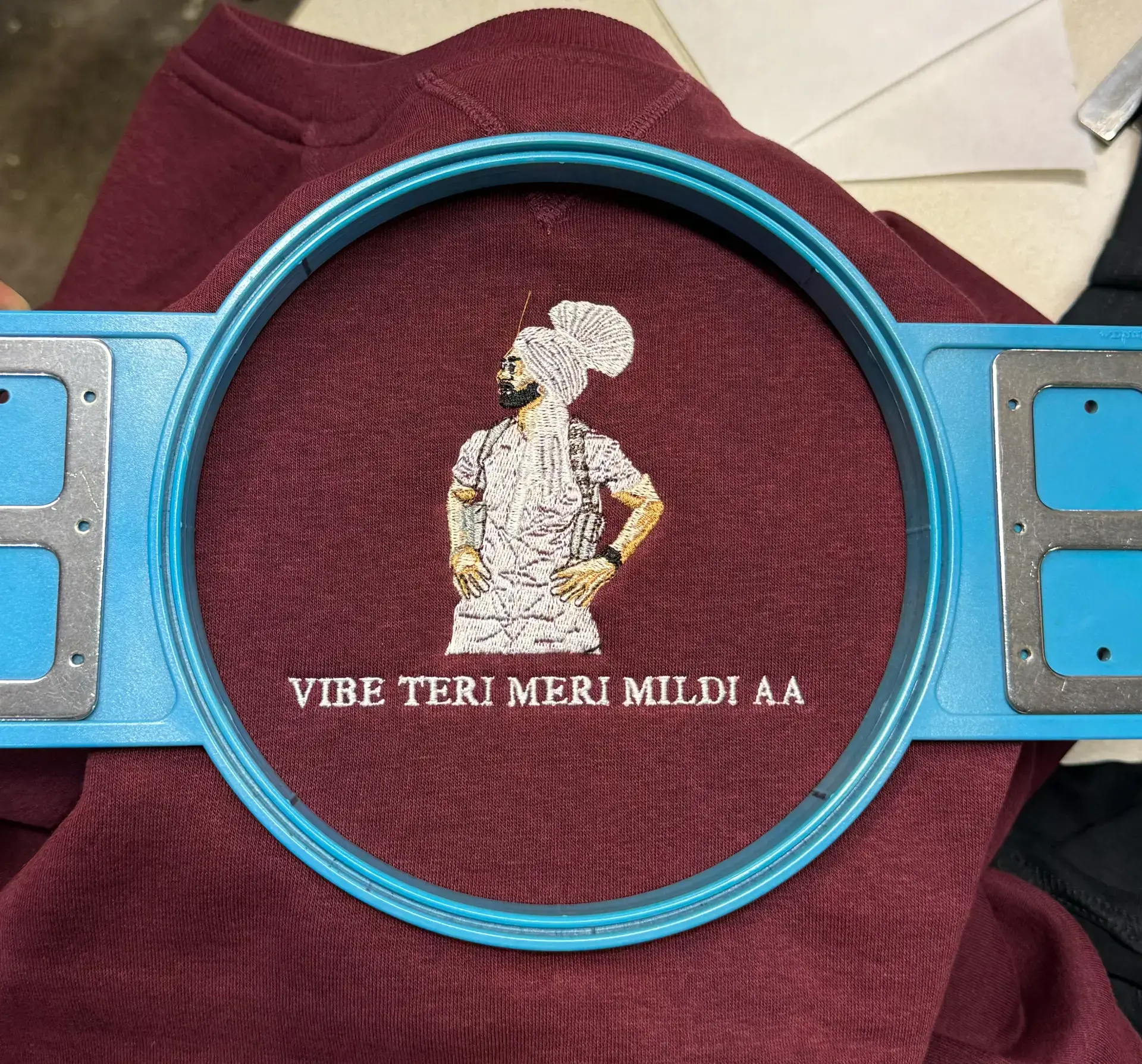 Detailed figure and lettering embroidered on maroon fabric