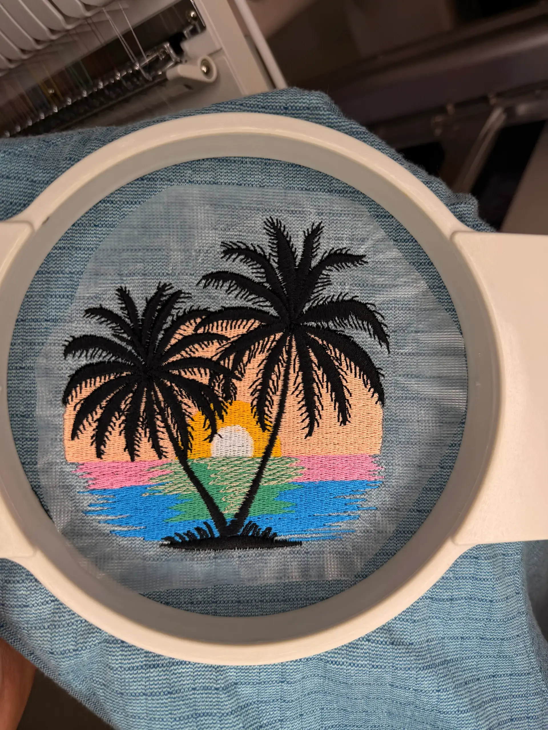 Detailed palm tree embroidery held in an embroidery hoop