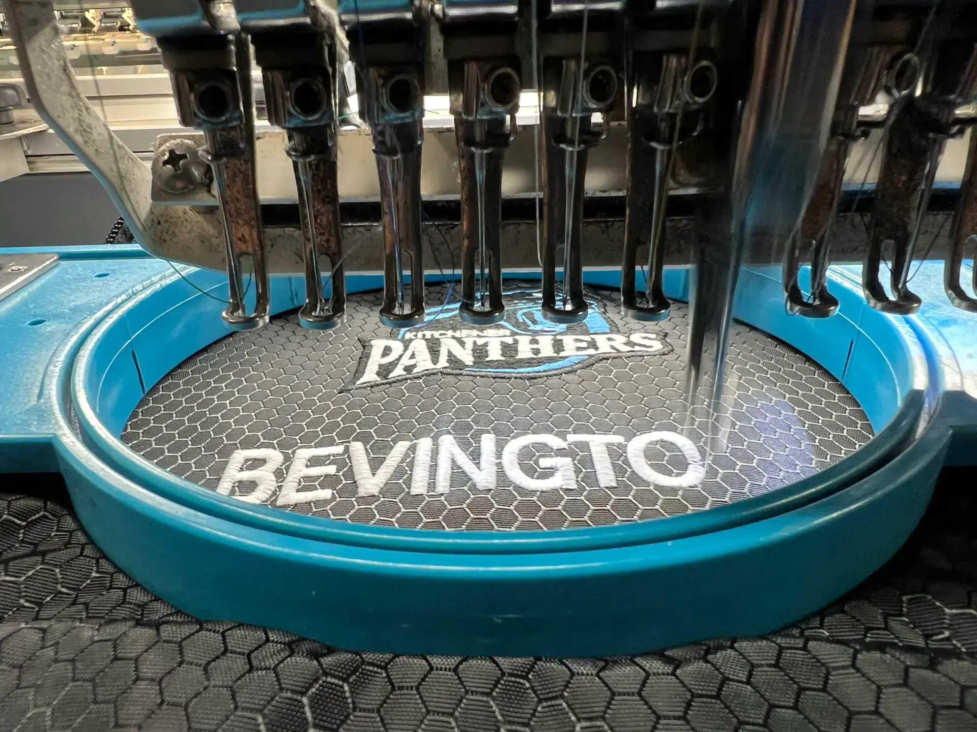 White business name embroidered on teal fabric