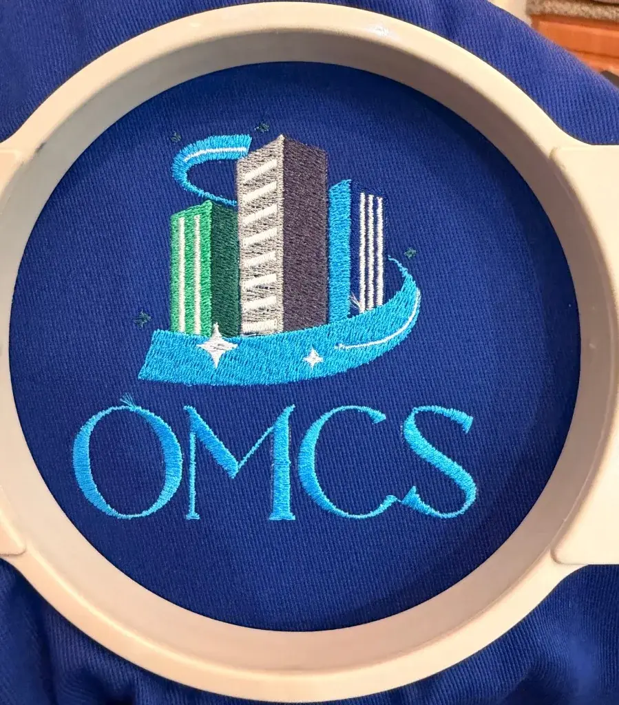 OMCS skyline logo embroidered in blue and green thread