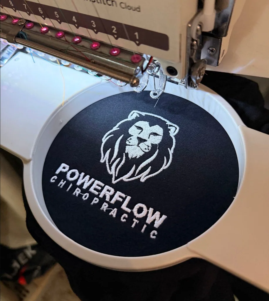 Powerflow Chiropractic lion logo embroidered in white on navy fabric